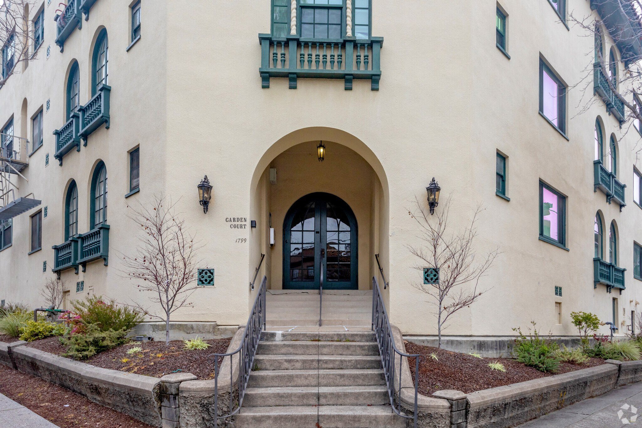 the front of a building with stairs and a large arched doorway